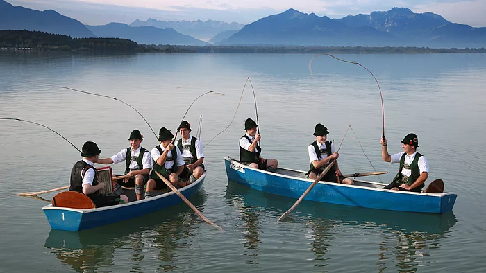 Chieminger Trachtenverein auf dem Chiemsee Goaßlschnalzer in Tracht sitzen in zwei Ruderbooten auf dem Chiemsee