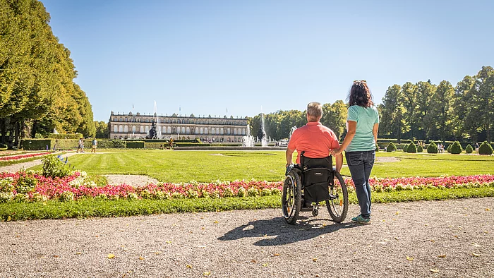 Schloss Herrenchiemsee mit Rollstuhlfahrer Rollstuhlfahrer vor der Kulisse von Schloss Herrenchiemsee